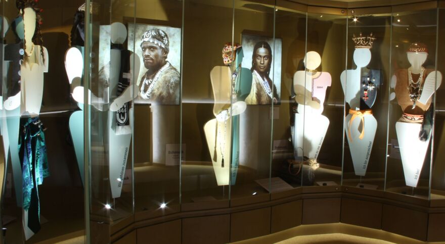 view of the exhibition room with silhouettes of people decorated with jewelry, in between drawings