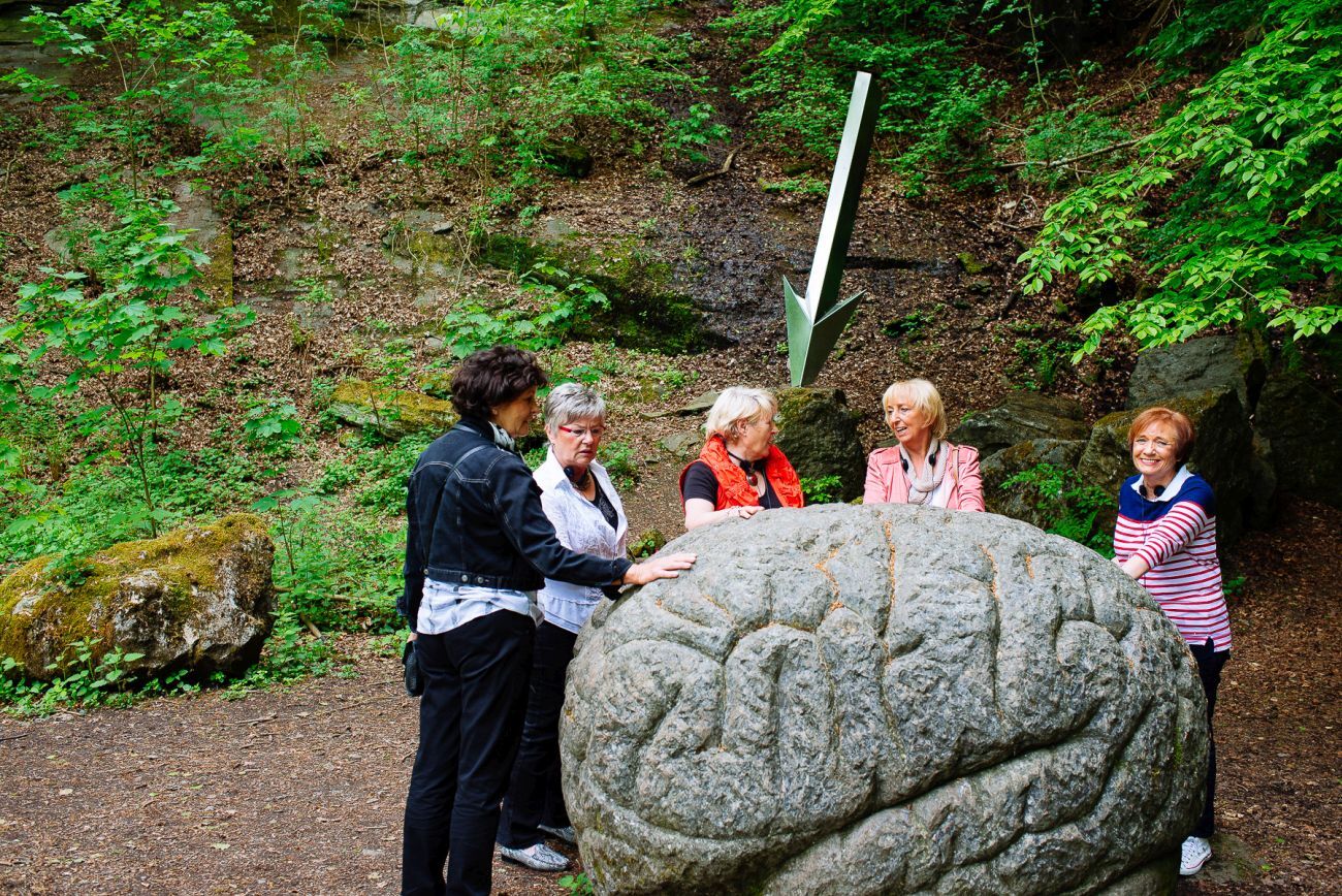 A group of visitors engaging with a huge stone sculpture along the Art Trail "Human Traces" at Neanderthal.