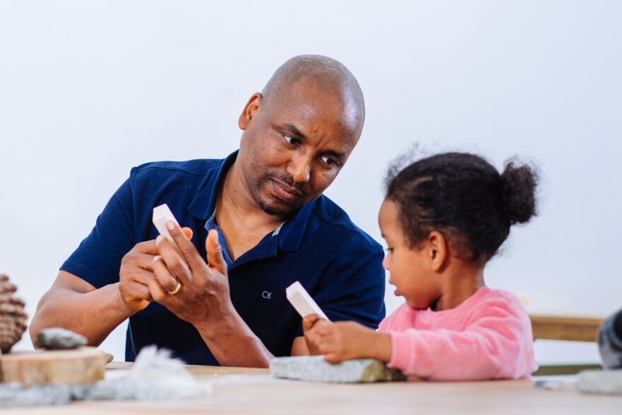 An adult and a kid engaged in a stone age workshop