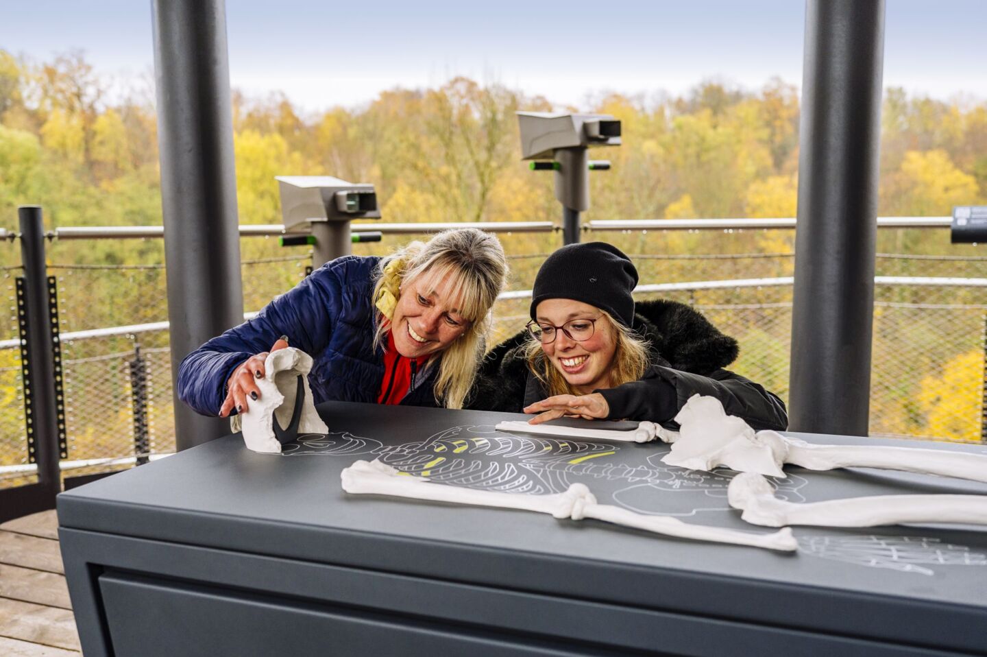 Two visitors at the tactile exhibit with the replicas of 16 Neanderthal bones in the centre of the uppermost platform of the Höhlenblick tower.