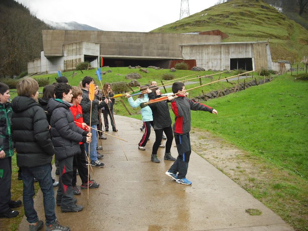 A group of students is practicing spear throwing in front of the museum.
