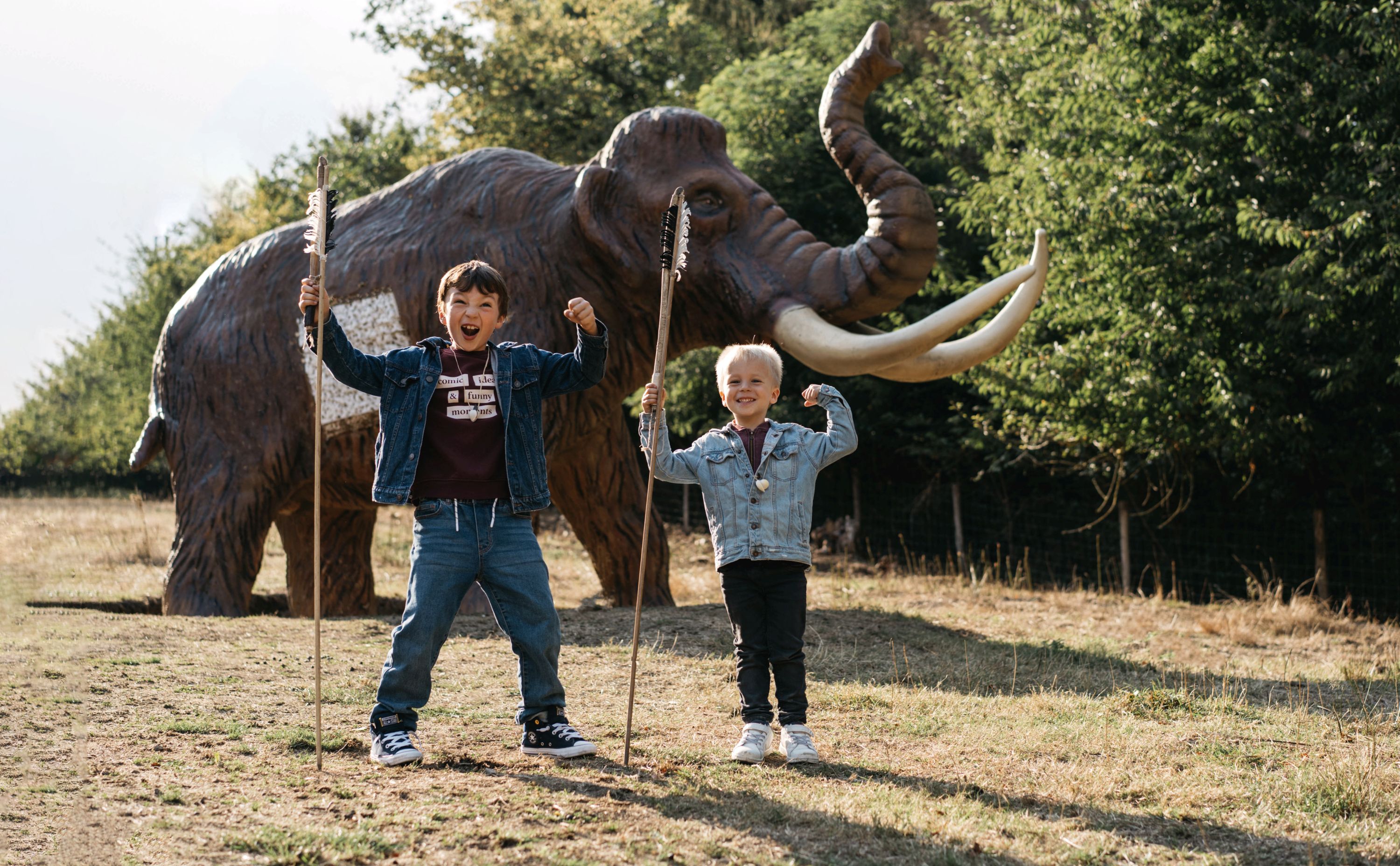 Children outdoors in front of a life-size replica of a mammoth