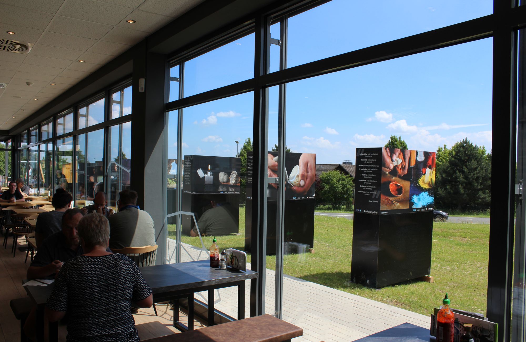 View of some large photo panels outside from the inside of a shopping mall cafe